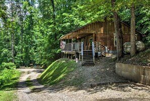 A rustic cabin with a porch, surrounded by dense forest.