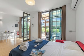 Ein Hotelzimmer mit Bett, Tisch mit Stühlen, einem Balkon und Klimaanlage.