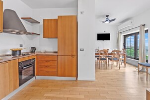Una cocina moderna con armarios de madera, horno empotrado y zona de comedor con mesa y sillas.
