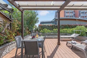 Ein überdachter Außenbereich mit Tisch und Stühlen, einem Liegestuhl und einem Pool.
