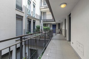 A corridor with a metal railing, a door, and a window on the right. - Mediterranea Apartments (Savona)