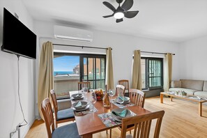 A dining area with a table set for four, a ceiling fan, and a television mounted on the wall. - Mediterranea Apartments (Savona)