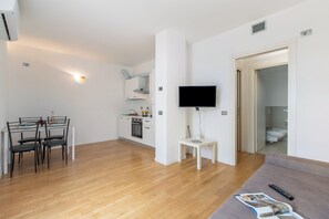 Un apartamento moderno con comedor, kitchenette, sala de estar y televisor.