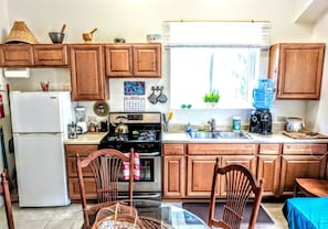 A kitchen with wooden cabinets, a refrigerator, stove, sink, and a dining table with chairs.