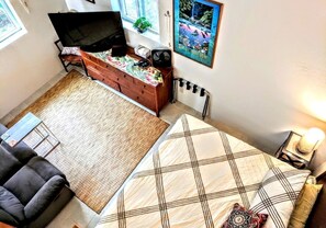 Ein Schlafzimmer mit Bett, Stuhl, Kommode, Fernseher, einem Poster und einer Heizung.