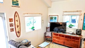 Un salon comprenant un canapé, un téléviseur, une commode en bois et une décoration sur le thème du surf.