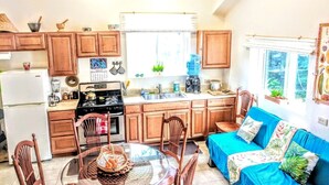 Une cuisine compacte dotée de meubles en bois, d’un réfrigérateur, d’une cuisinière et d’un coin repas avec une table et des chaises.