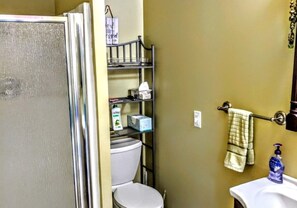 Ein Badezimmer mit Toilette, Waschbecken, Ablagefach für Toilettenartikel und Handtuchhalter.