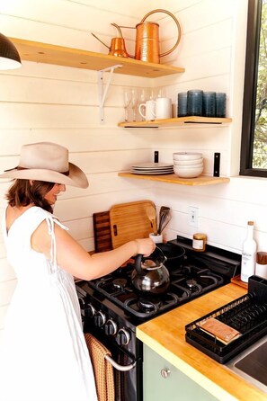 A kitchen with a stove, a kettle, and various kitchen utensils.