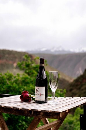 A bottle of wine and a glass on a wooden table with a scenic view.
