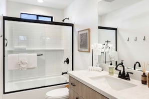 A modern bathroom with a glass-enclosed shower, a white toilet, a marble sink, and a large mirror. - Fantastic Vacation Rental with Fire Pit and Gorgeous Desert Views in Yucca Valley, California (Yucca Valley)