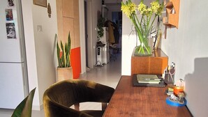 En spiseplads med et træbord, en velourstol og krukker med planter.