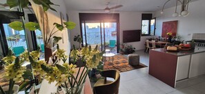 A modern kitchen with a dining area, a balcony with plants, and a large window. - Bright & Stylish Boho Home w\ Botanical Terrace, by a grove -with a safe Mamad (Tel Aviv-Yafo)