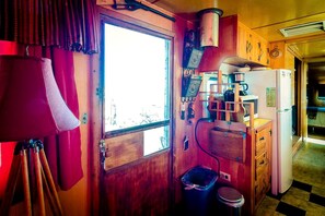Eine kleine Küche mit Fenster, Spüle, Kühlschrank und einem Holzschrank.