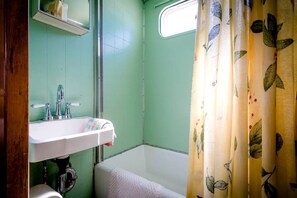 A bathroom with a sink, a shower, and a window. - Superb Elevated Trailer for Unique Vacation in San Bernardino County, California (Joshua Tree)