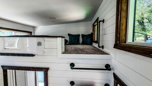A loft bedroom with a bunk bed, a window with a view of trees, and a white ceiling. - Cozy Modern Tiny Home with Panoramic Light & Starry Skies near Palomar Observatory, Pauma Valley, California (Pauma Valley)