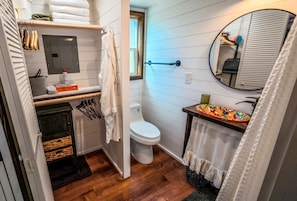 Un baño pequeño con inodoro, lavamanos con detalles de azulejos decorativos, toallero y espejo.