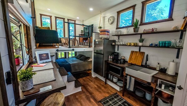 Una cocina compacta con refrigerador, estufa y repisas de madera.