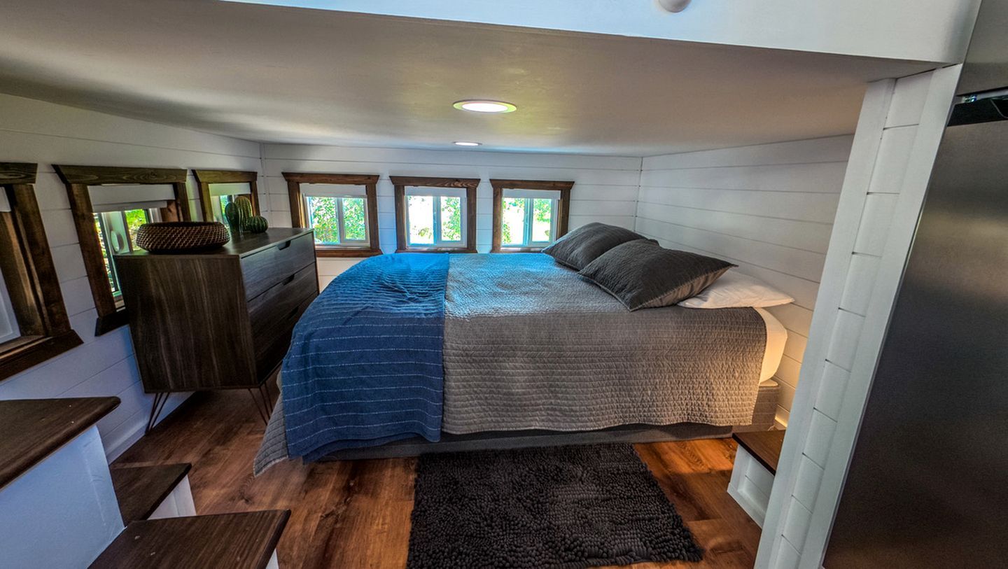 A bedroom with a bed, a dresser, a window, and a ceiling light.
