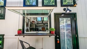 Una cocina con ventana, puerta y un pequeño espacio de estar al aire libre.