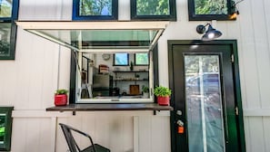 Una cocina con ventana, puerta y un pequeño espacio de estar al aire libre.