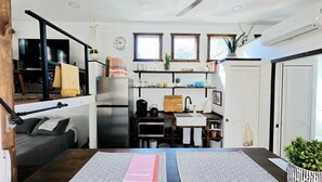 Cocina compacta con refrigerador, microondas y pileta. Pequeño comedor con mesa y sillas.