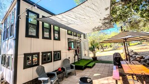 Un porxo cobert amb seients exteriors, una barbacoa i una petita zona de piscina.