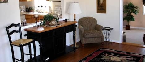 A kitchen with wooden cabinets, a dining table, two chairs, a lamp, and a rug.