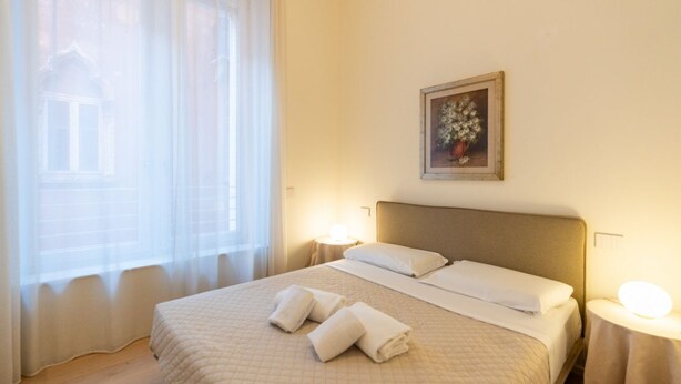 A hotel room with a large bed, a painting on the wall, and a window with sheer curtains. - Corte Farina Residence, 1st Floor (Verona)