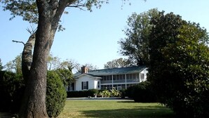 A large house with a covered porch, surrounded by trees and a well-maintained lawn.
