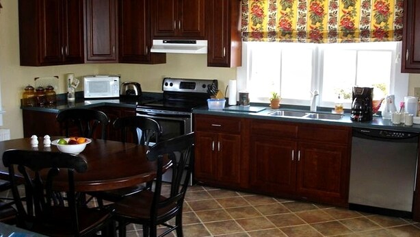 A kitchen with dark wooden cabinets, a stove, a microwave, and a dishwasher.
