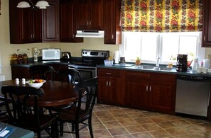 Una cocina con armarios de madera oscura, estufa, microondas y lavavajillas.