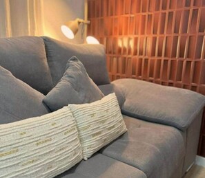 A grey sofa with a textured pillow and a wall with vertical wooden slats. - Luz Suite Seville Downtown 2026 (Seville)