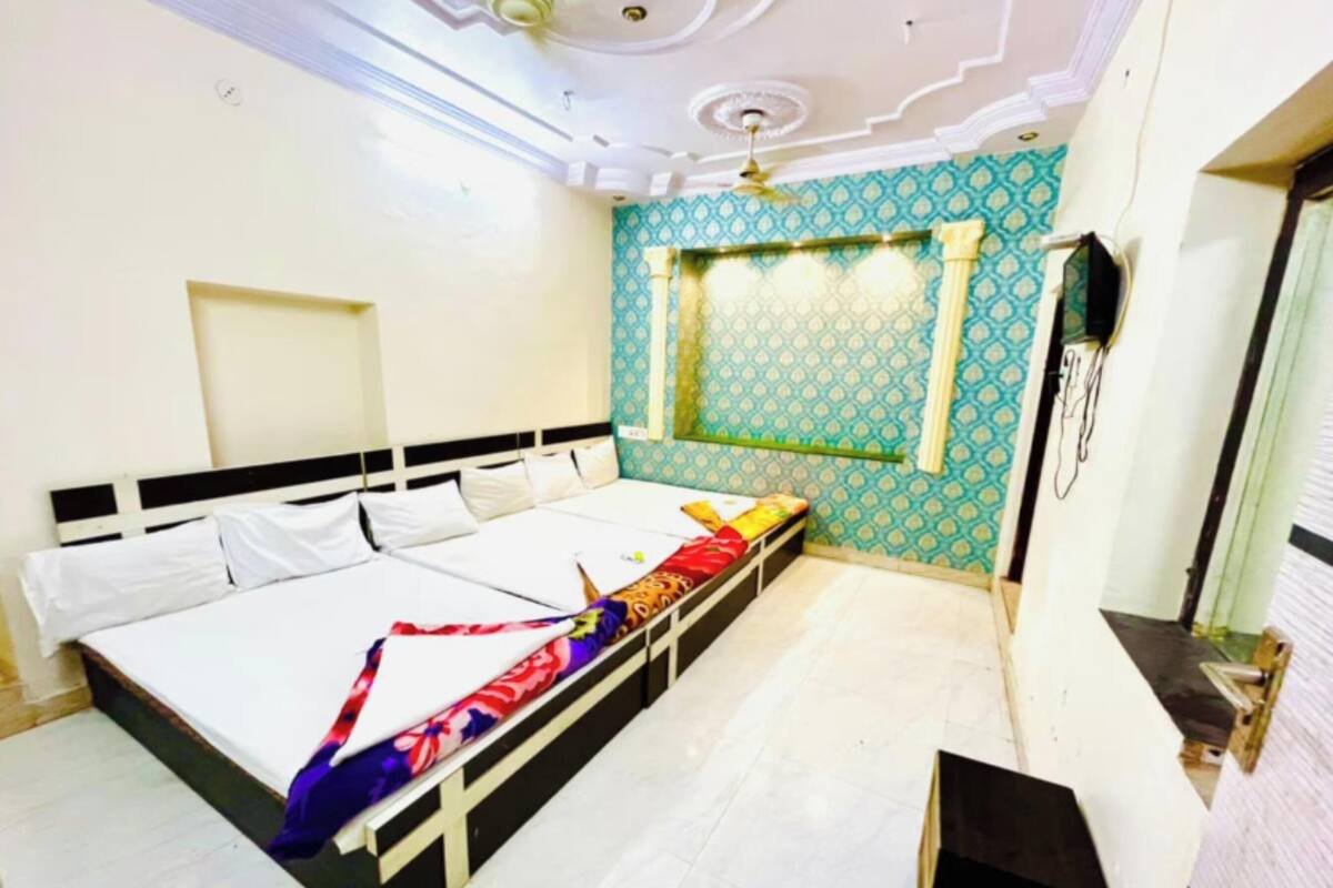 Ein Schlafzimmer mit einem Bett, einem Deckenventilator, einem an der Wand montierten Fernseher und Wandtapete mit Muster.