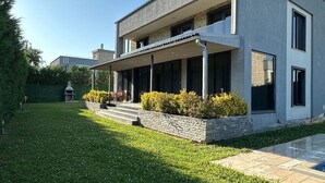 Une maison moderne à deux étages, dotée d’un porche abrité, d’une pelouse bien entretenue et d’un mur de soutènement en pierre.