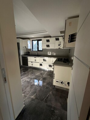 Una cocina moderna con armarios blancos, un refrigerador de acero inoxidable y piso de baldosas.