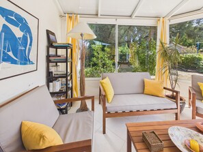 Ein sonnendurchfluteter Raum mit einer Couch, einem Holztisch und einem Bücherregal.