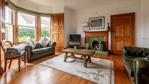Una sala de estar con chimenea, un sofá, un televisor y una mesa de centro de madera.