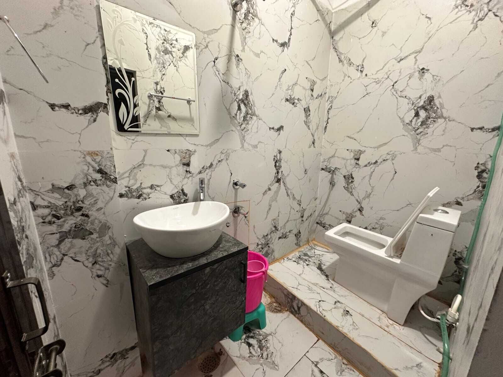 A bathroom with a marble sink, a toilet, and a shower.