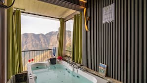 A bathroom with a bathtub, a shower, and a view of mountains. - Highlanders Cafe Stay (Mussoorie)