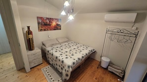 Ein Schlafzimmer mit einem Bett, einer Pendelleuchte, einer Wand-Klimaanlage und einem Kleiderhaken.
