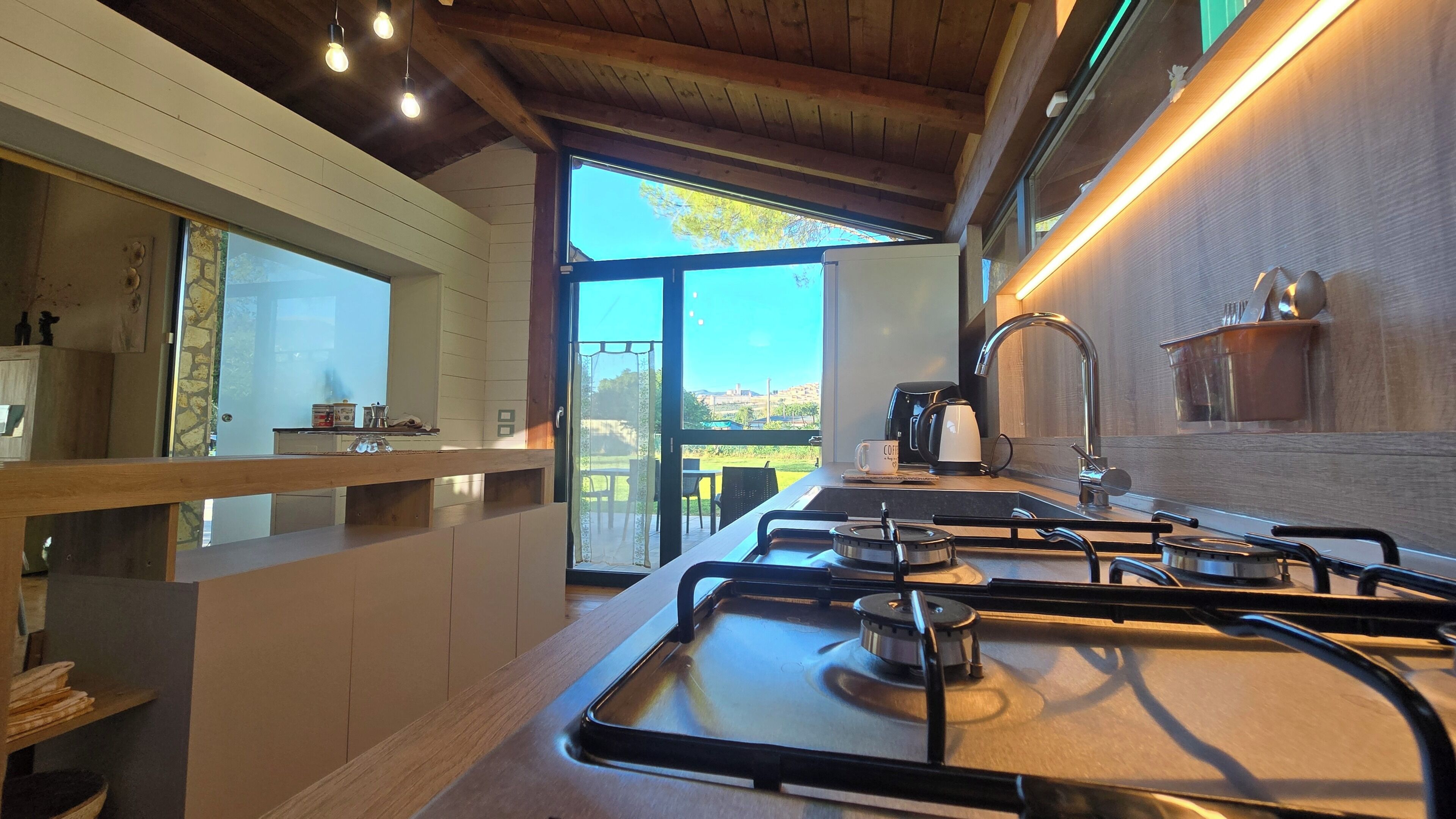A modern kitchen with a gas stove, a coffee maker, and a view of the outdoors.