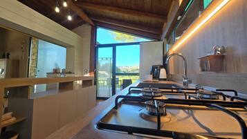 A modern kitchen with a gas stove, a coffee maker, and a view of the outdoors.