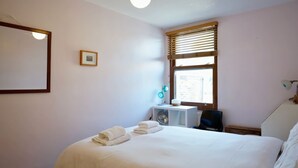 A bedroom with a bed, a desk, a chair, a window with blinds, a picture on the wall, and a lamp. - Cosy 1BDR Flat in Nunhead by Peckham Rye Park (Greater London)