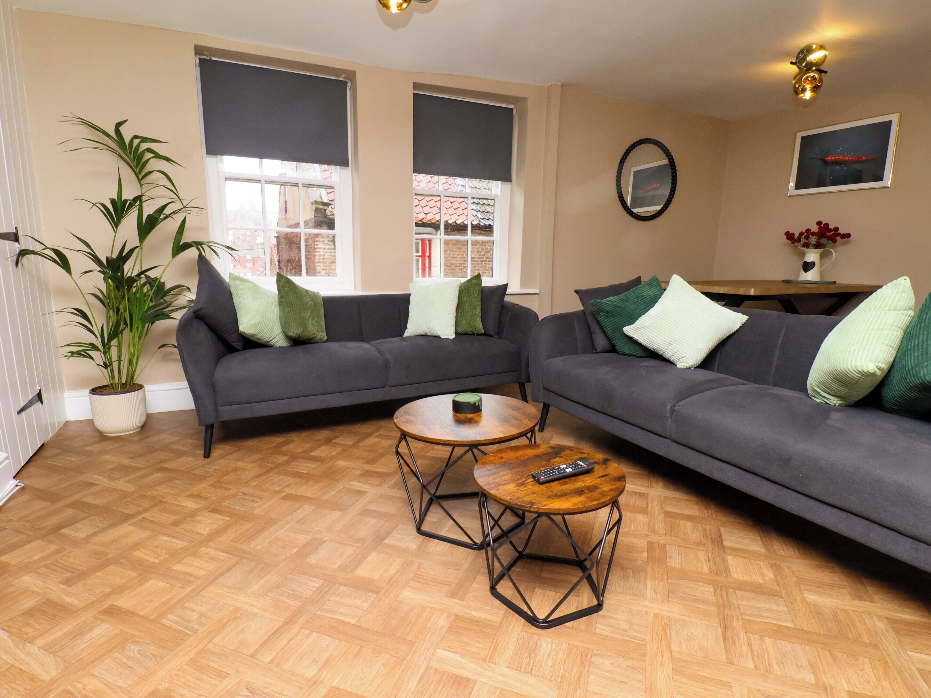 A living room with two grey sofas, a wooden coffee table, and a potted plant.