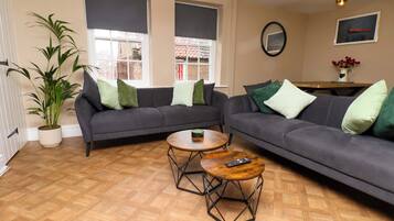 A living room with two grey sofas, a wooden coffee table, and a potted plant.