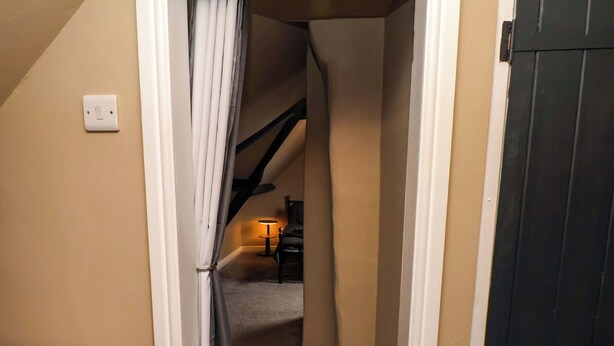 A narrow hallway with a ceiling fan, a lamp, and a door leading to another room. - G's Loft (Whitby)
