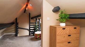 A hallway with a wooden dresser, a potted plant, and a staircase.