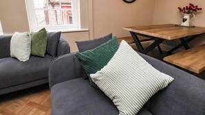 A living room with a sofa, a table, and a window with a view of buildings. - G's Loft (Whitby)