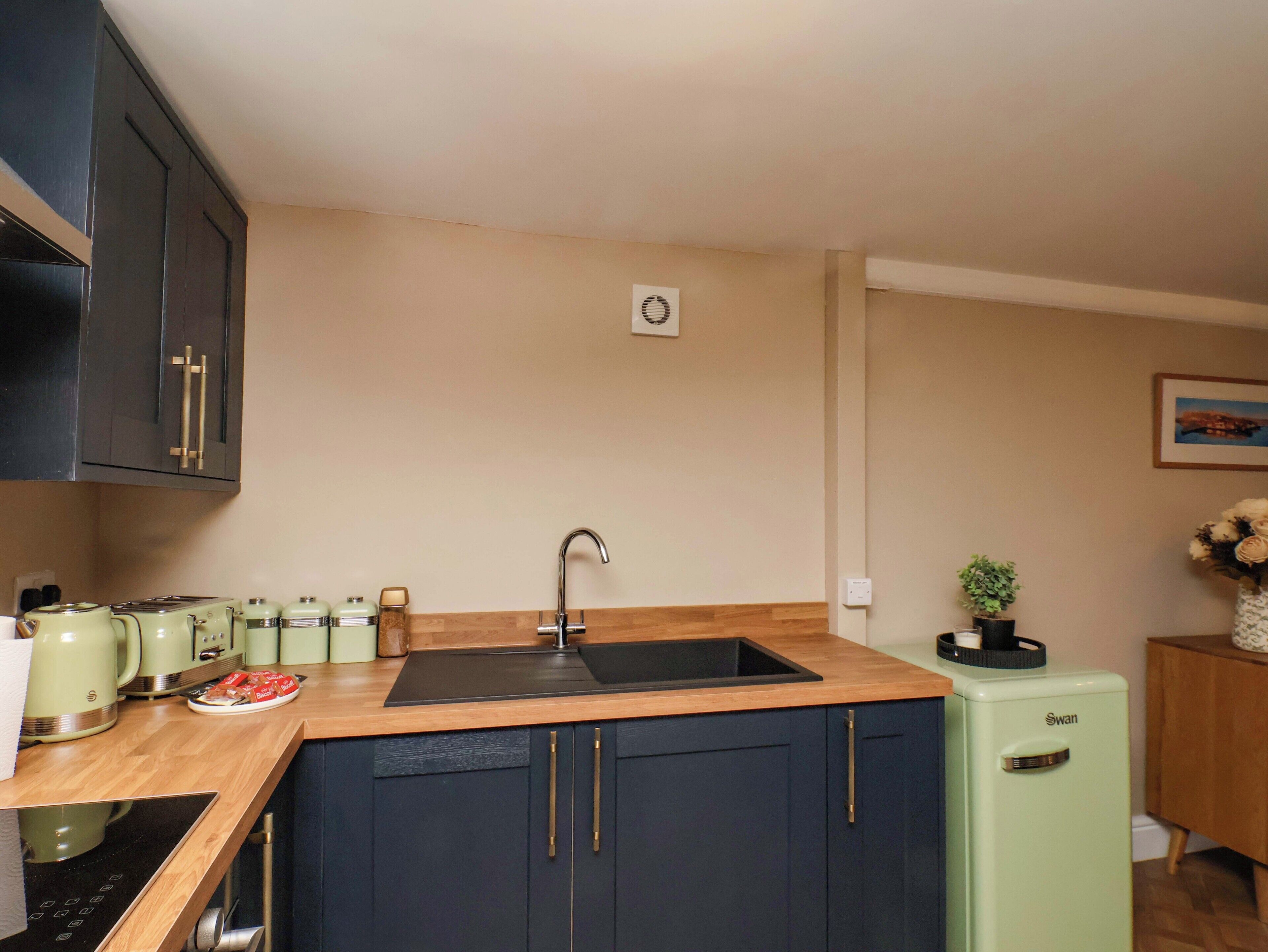 A compact kitchen with a sink, countertop, and a small refrigerator.